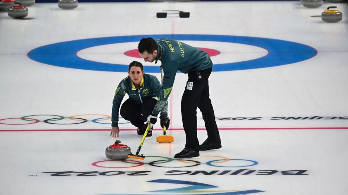Australias Tahli Gill (L) curls the stone as Australias Dean Hewitt (R) sweeps during the mixed doubles round robin session 7 game of the Beijing 2022 Winter Olympic Games curling competition between Australia and Norway, at the National Aquatics Centre i